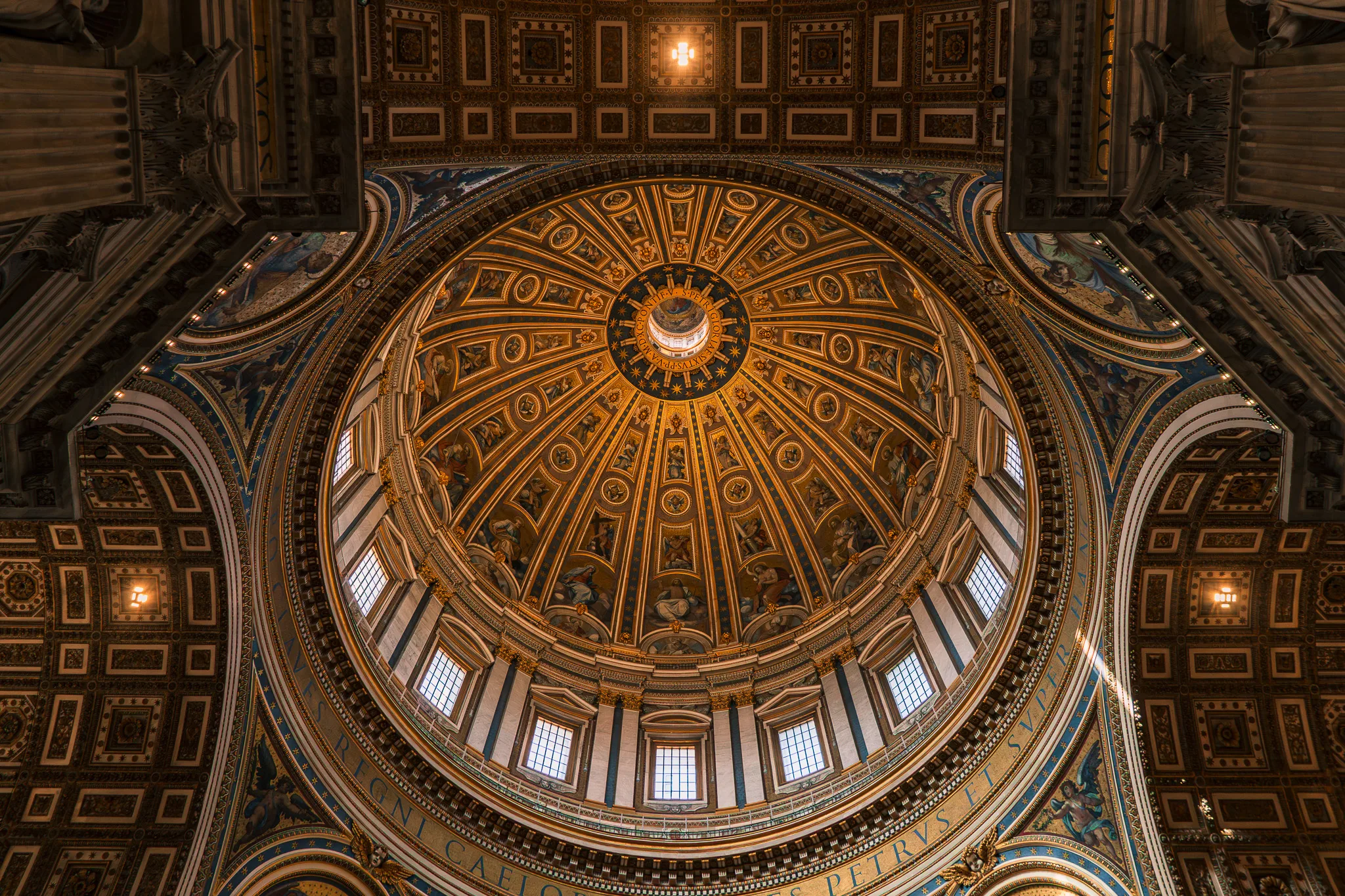 Kopuła Bazyliki św. Piotra w Watykanie – bogato zdobione wnętrze z mozaikami, złotymi ornamentami i promieniami światła wpadającymi przez okna.