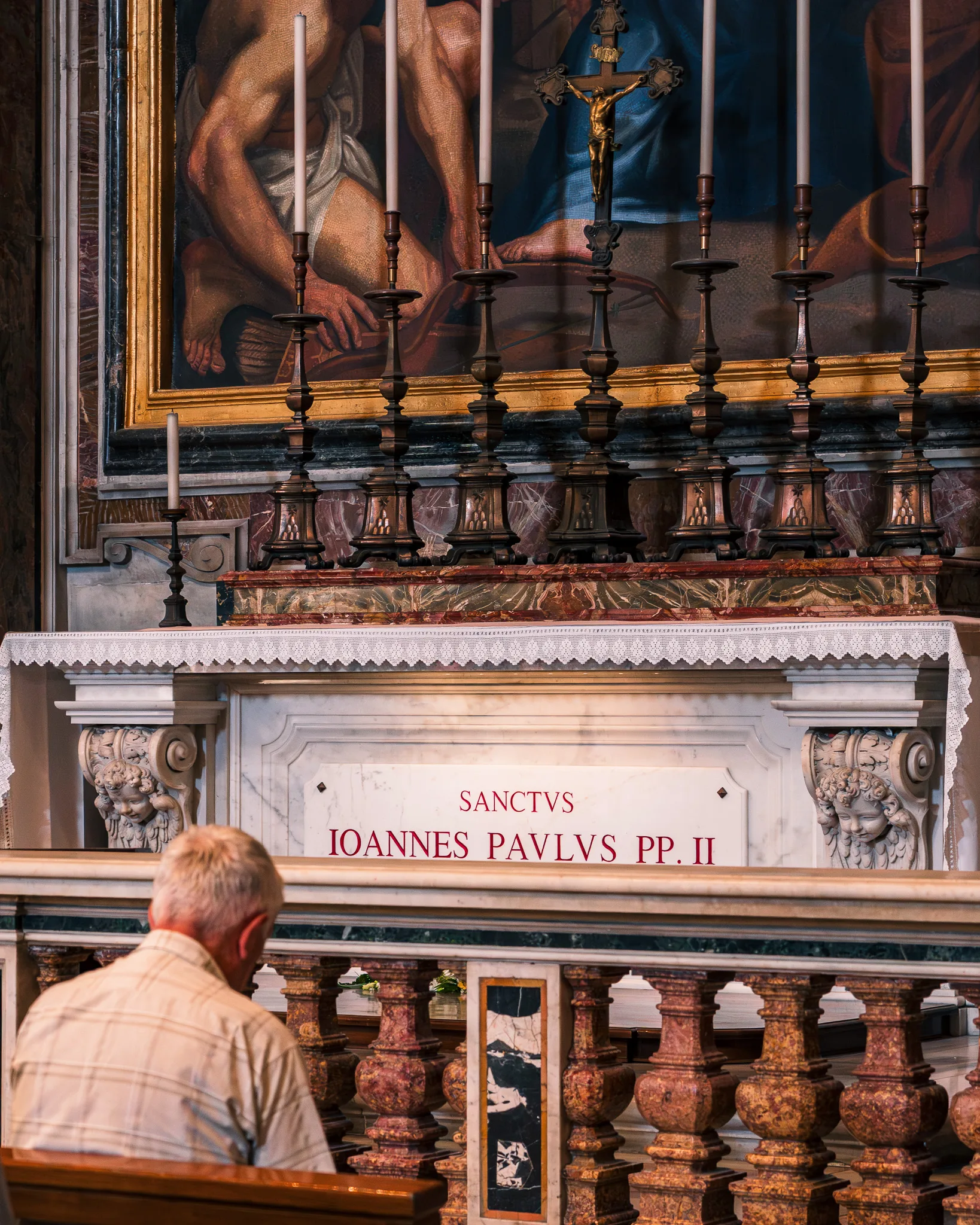 Grób św. Jana Pawła II w Bazylice św. Piotra w Watykanie, przed którym modli się mężczyzna.
