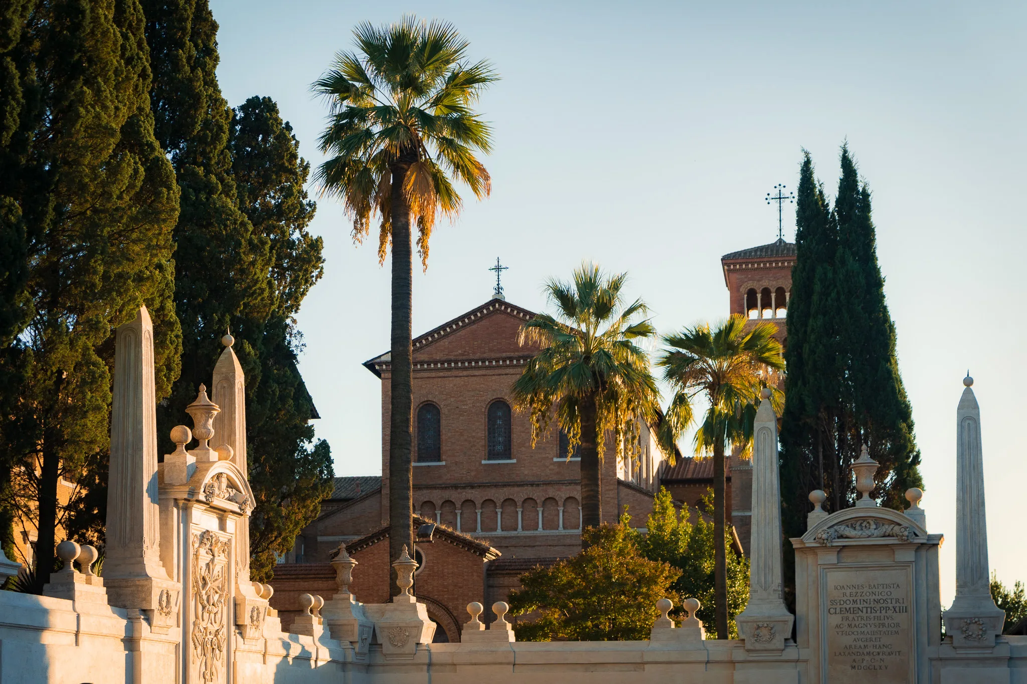Bazylika Santa Sabina na wzgórzu Awentyn w Rzymie, otoczona palmami i cyprysami w złotym świetle popołudnia