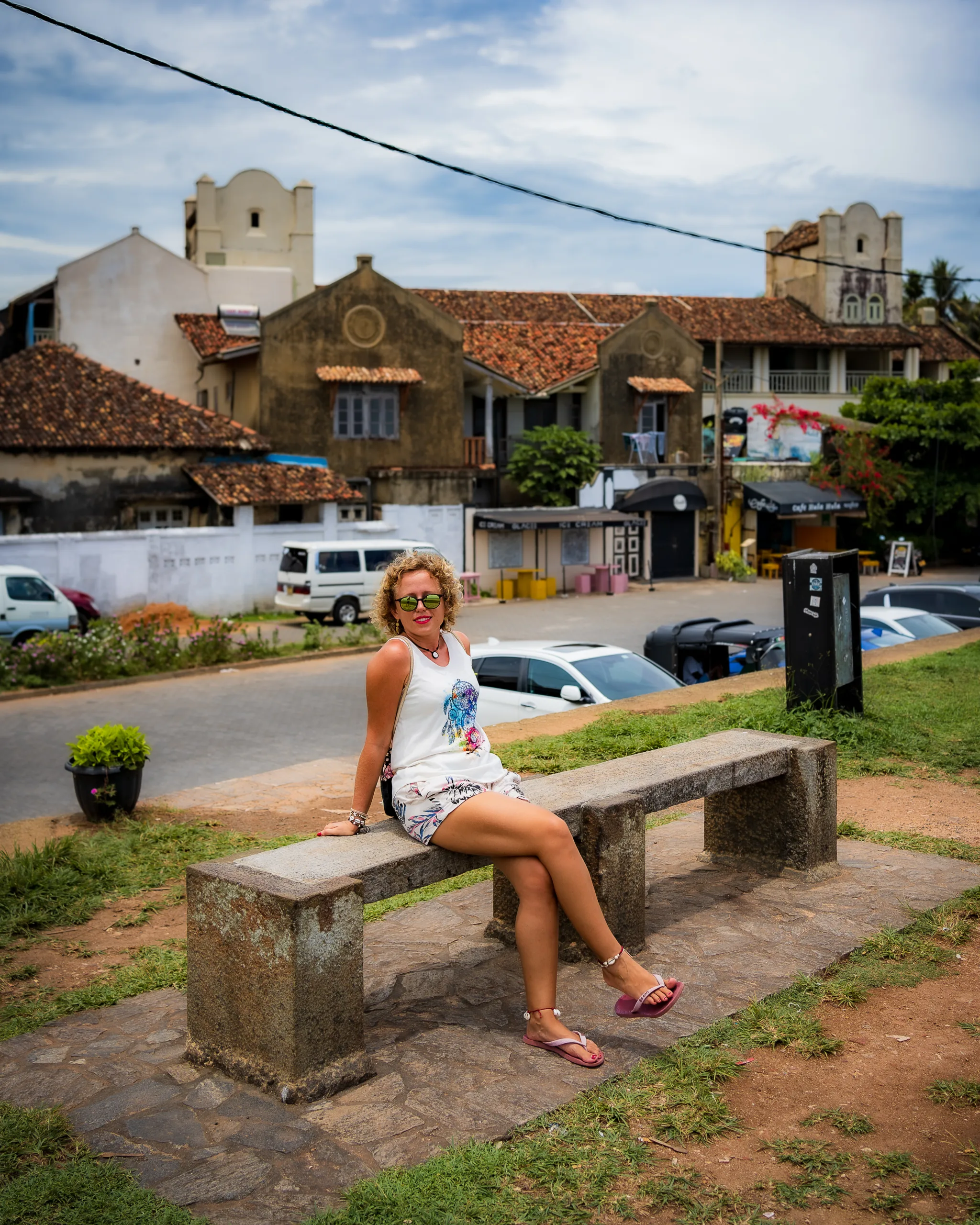 Turystka odpoczywa na ławce z widokiem na kolonialne budynki w Galle, Sri Lanka.