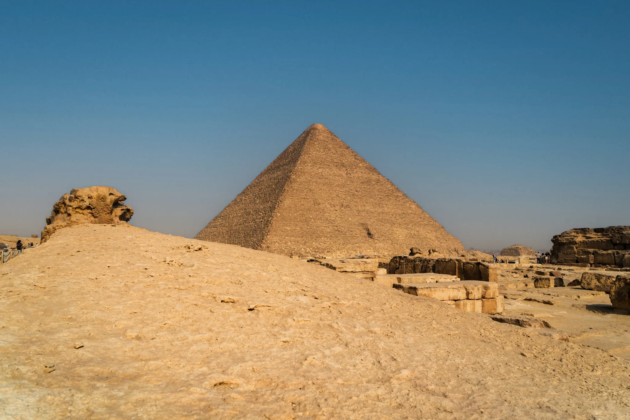 Piramida Cheopsa (Wielka Piramida) na płaskowyżu Gizy, otoczona skalistym terenem.