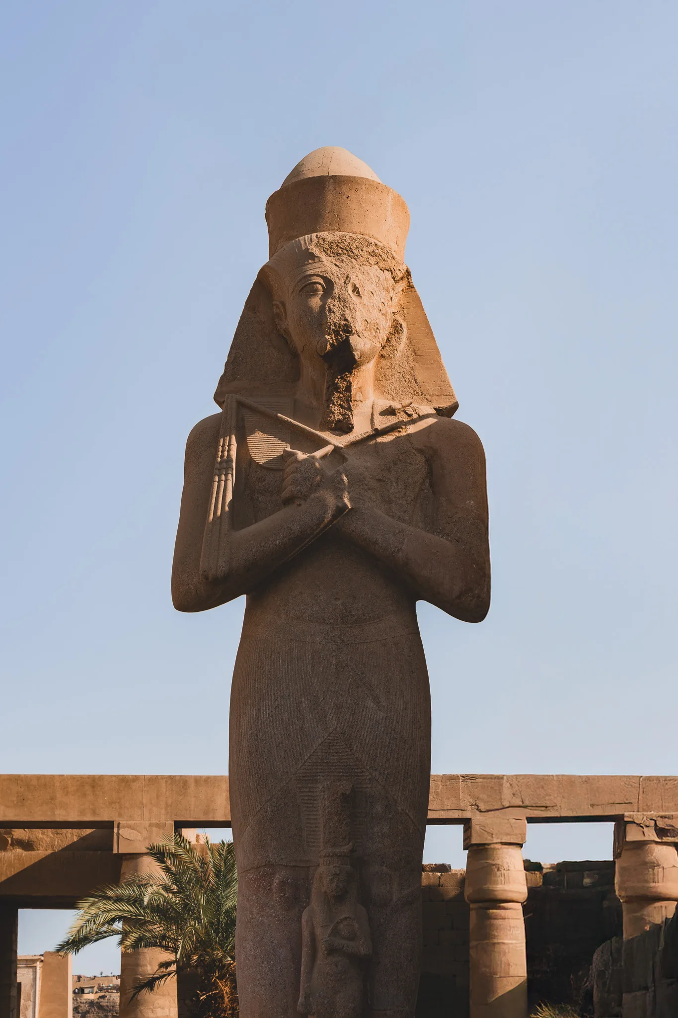 Ruiny kolumn i starożytnych murów kompleksu świątynnego Karnak na tle czystego, błękitnego nieba.