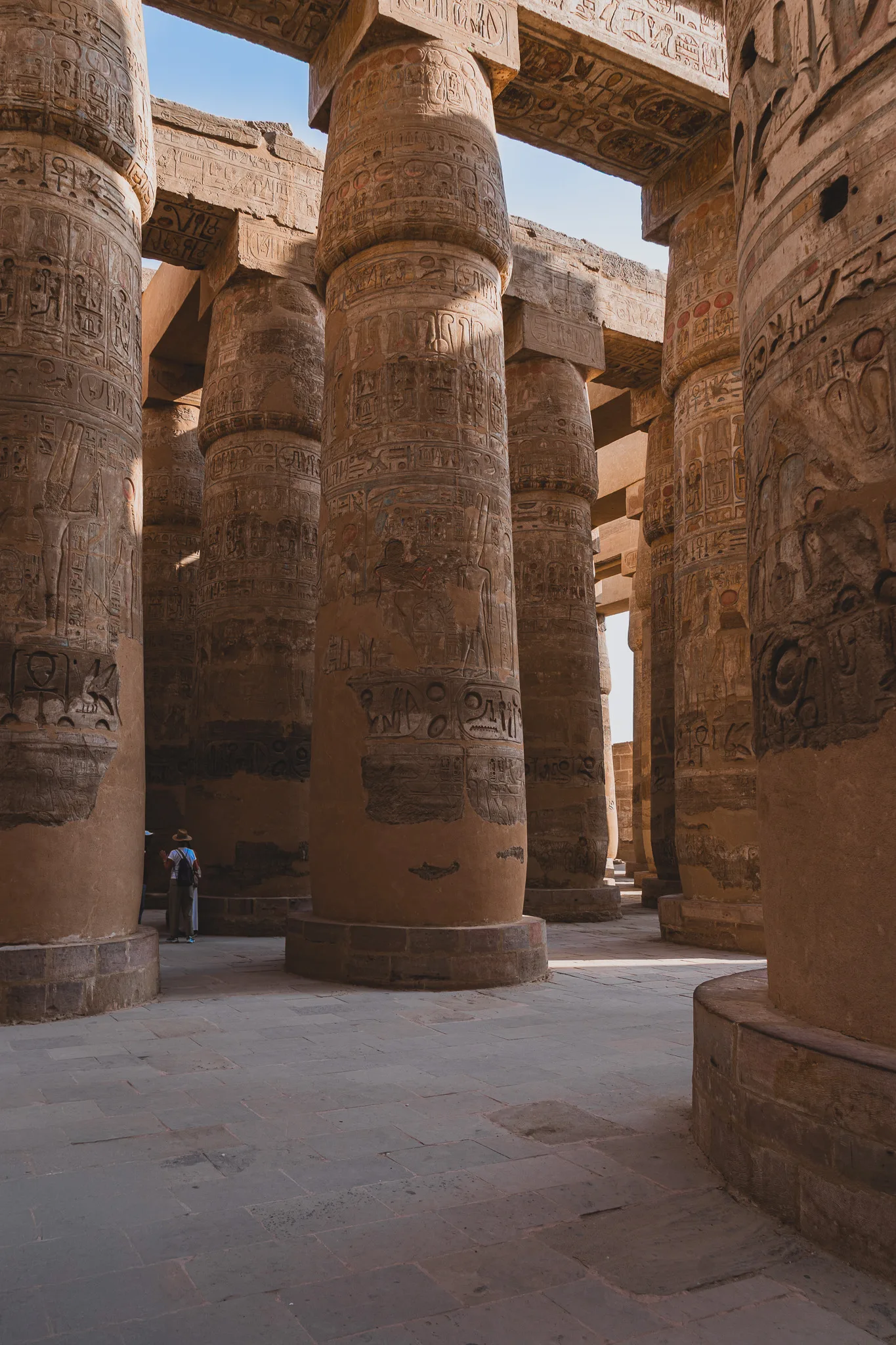 Rzędy monumentalnych kolumn pokrytych hieroglifami w świątyni Karnak w Luksorze.