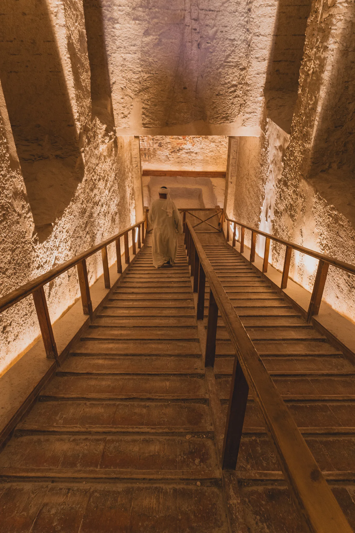 Schody prowadzące w dół do komory grobowej w Dolinie Królów, oświetlone ciepłym światłem.