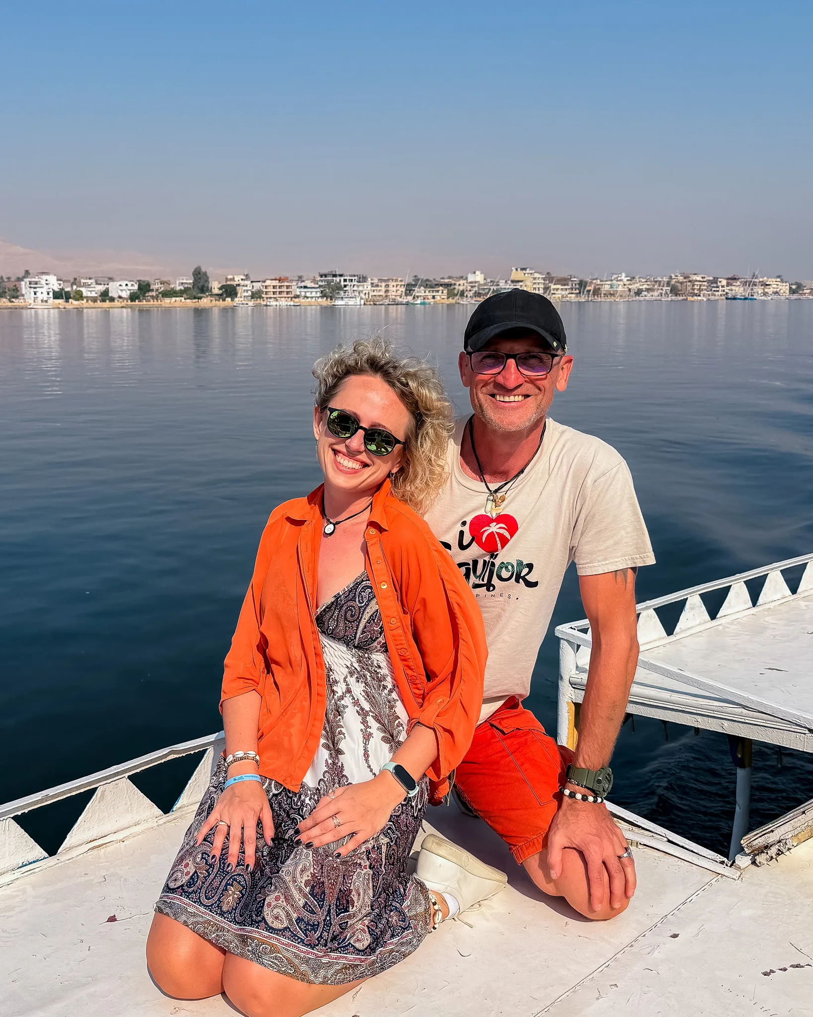 Agata i Paweł pozują na łodzi na Nilu, w tle panorama miasta Luksor oraz spokojna tafla wody.
