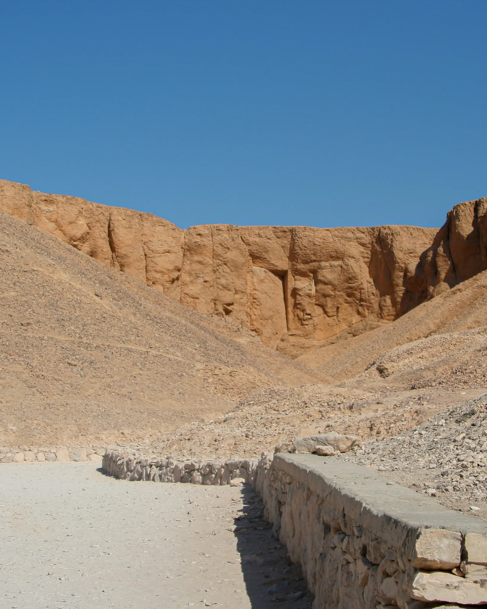 Pustynny krajobraz Doliny Królów; kamienna ścieżka prowadzi w stronę skalnych wąwozów i ukrytych grobowców faraonów.