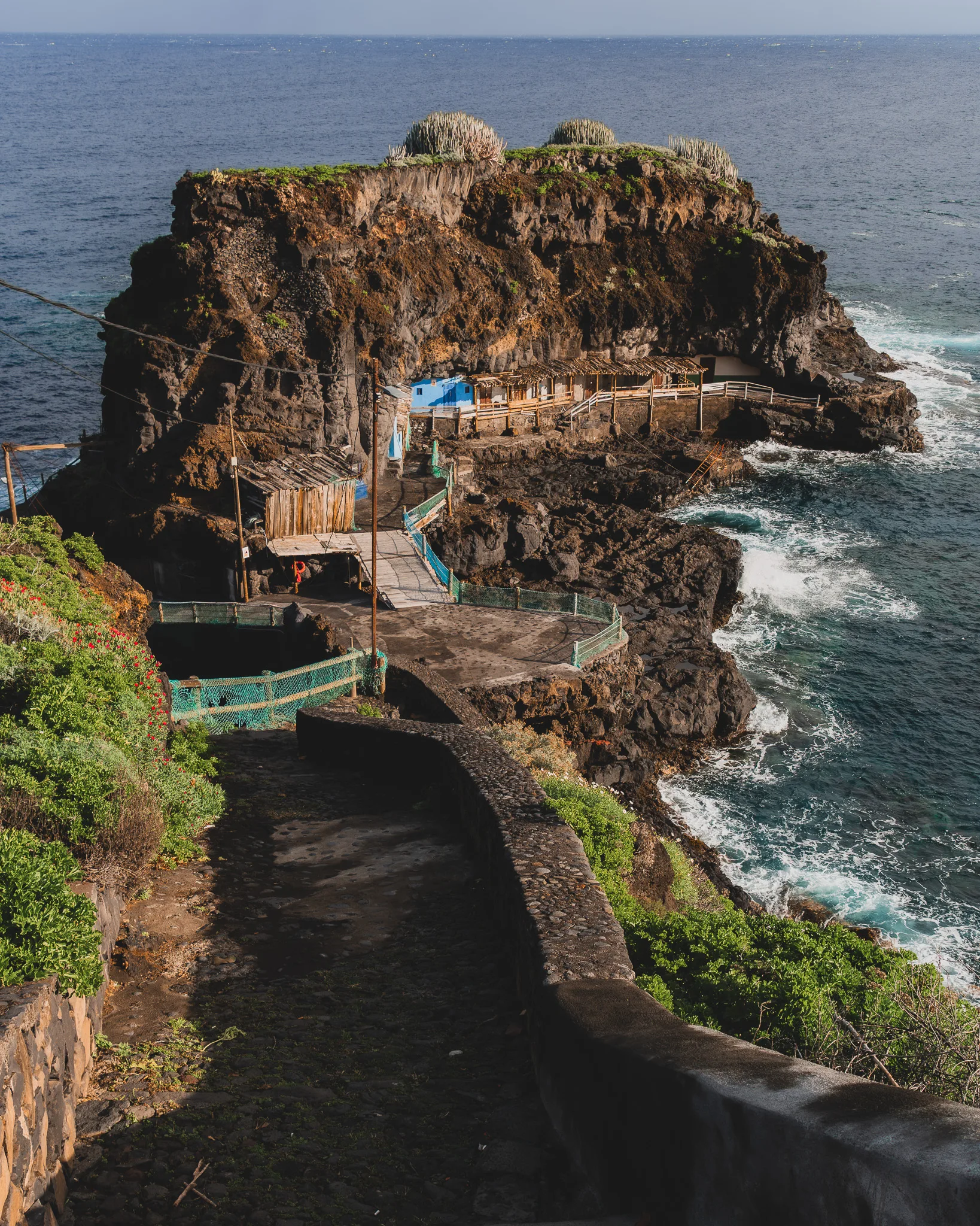 Skalista zatoka z pomostami i niewielkimi zabudowaniami nad oceanem, fale rozbijające się o brzeg - Puerto de Talavera - La Palma