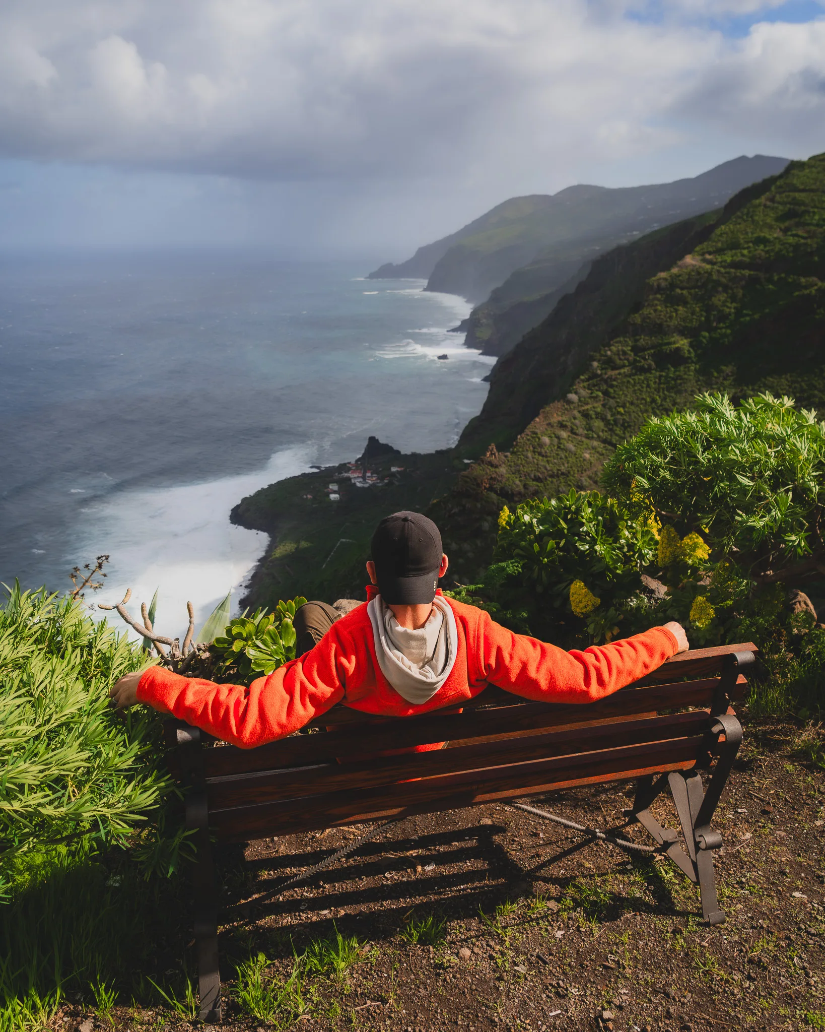 Osoba siedząca na ławce z widokiem na klifowe wybrzeże La Palmy i ocean w tle