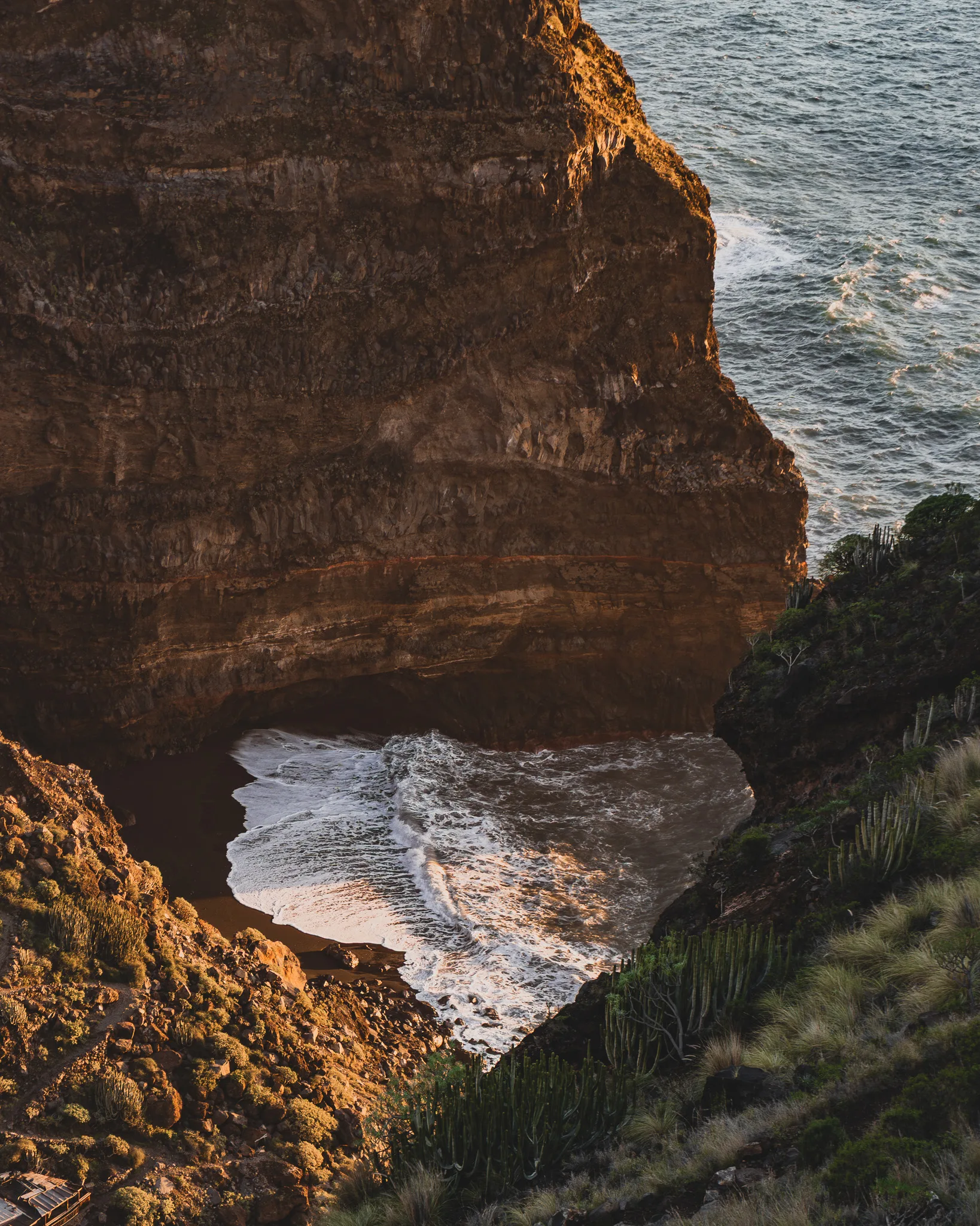 Zatoka u podnóża wysokiego klifu na La Palmie, fale oceanu rozbijające się o skały.