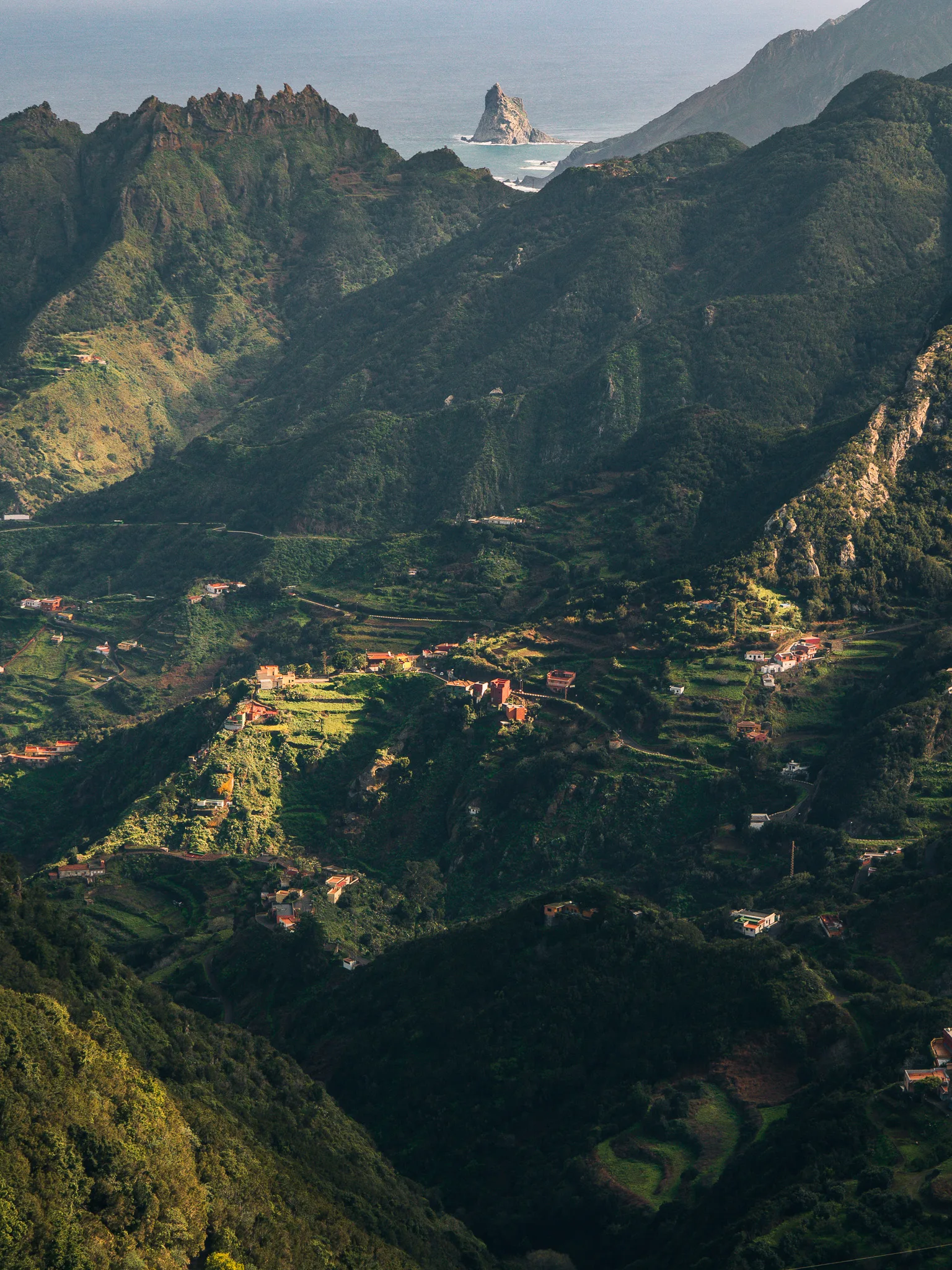 Zielone doliny masywu Anaga na Teneryfie z tarasami uprawnymi i rozproszonymi domami, w tle Atlantyk i skalista wysepka Roque de Anaga