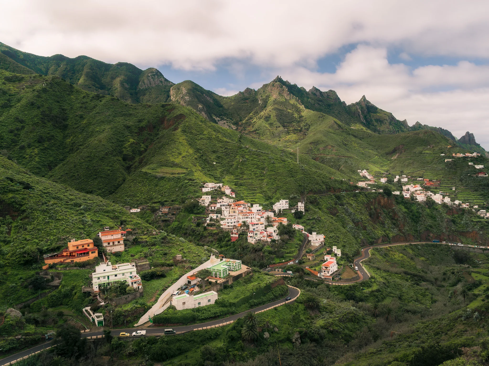 Górska wioska w masywie Anaga na Teneryfie, białe domy na zielonych zboczach i kręta droga wśród gór
taganana
