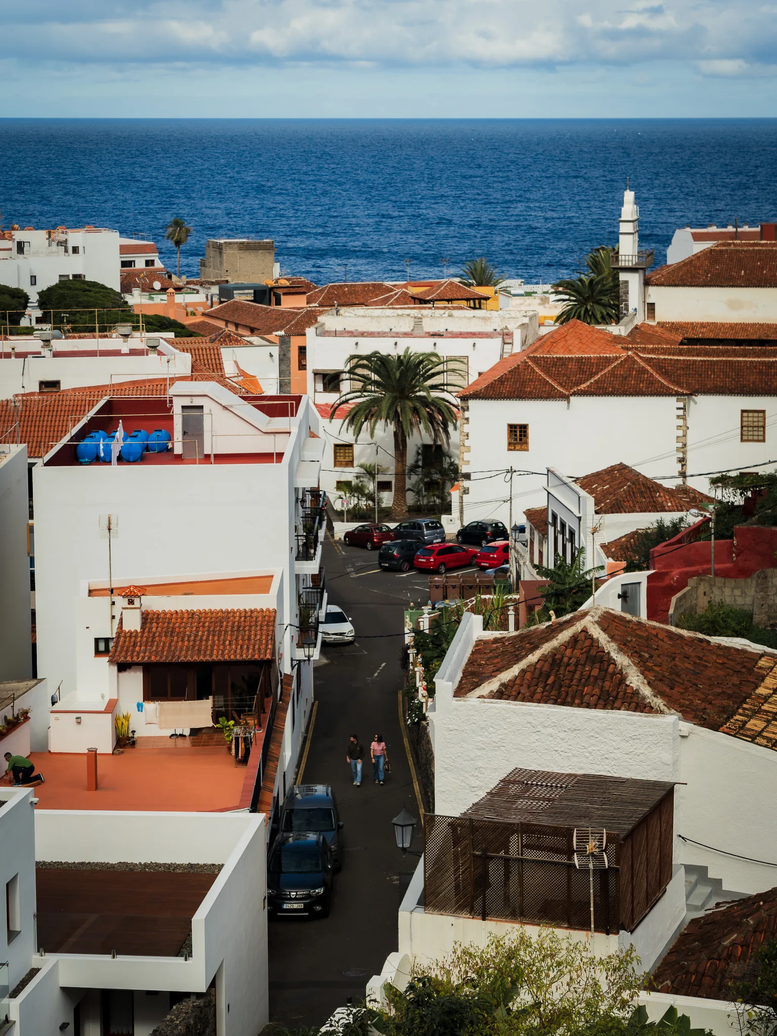 Garachico z lotu ptaka – białe domy z czerwonymi dachami, wąska uliczka prowadząca w stronę oceanu i błękitna tafla Atlantyku w tle.