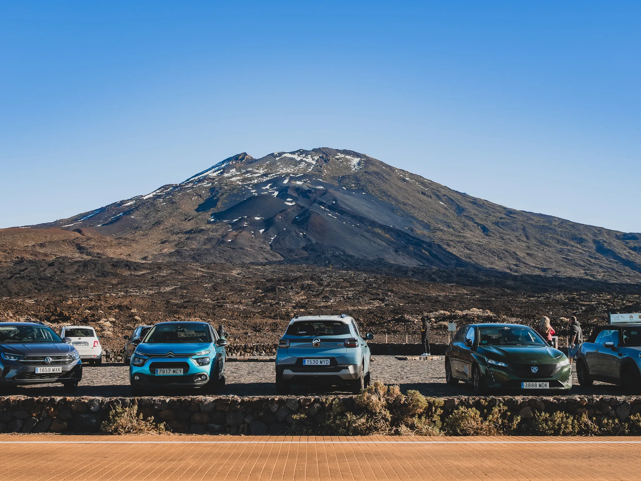 Parking przy Parku Narodowym Teide z zaparkowanymi samochodami na tle wulkanu Teide i surowego, lawowego krajobrazu Teneryfy.