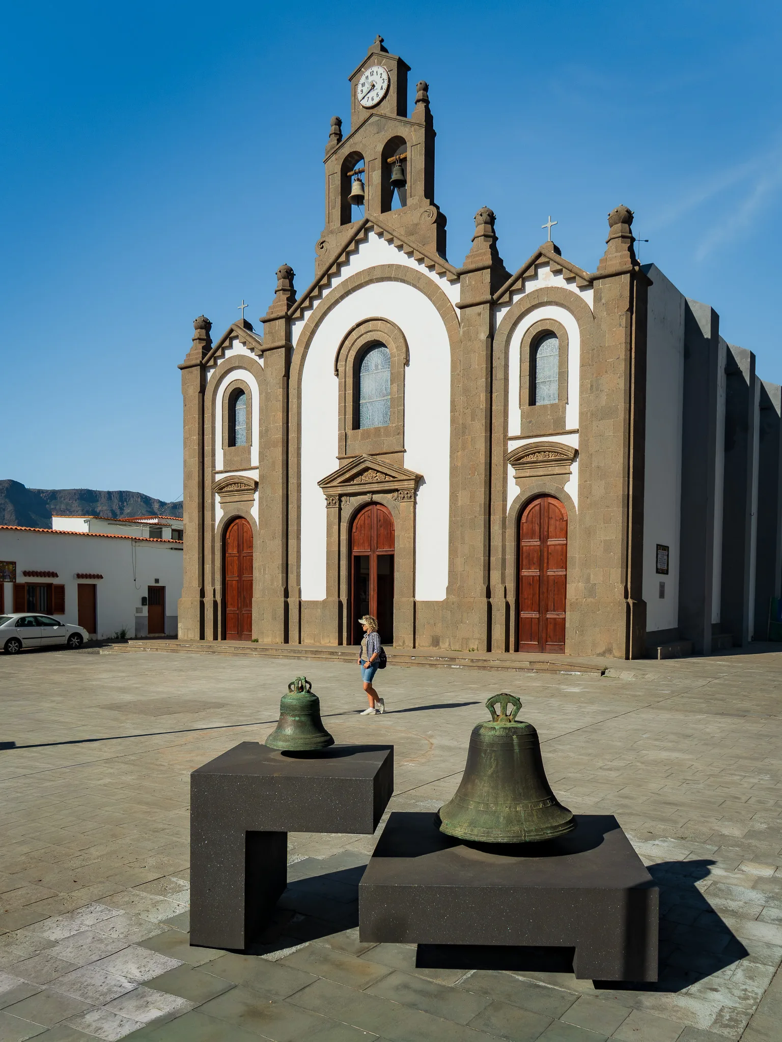 Gran Canaria: kościół z wieżą zegarową i dzwonami na placu, na pierwszym planie dwie zabytkowe dzwonnice
