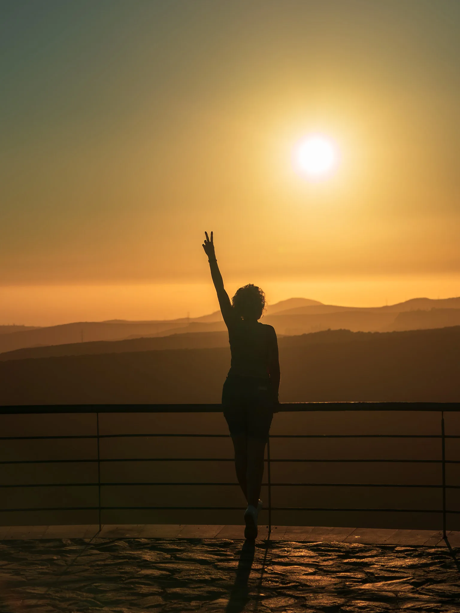 Sylwetka osoby na punkcie widokowym o zachodzie słońca, złota godzina i warstwowe góry w tle - Gran Canaria