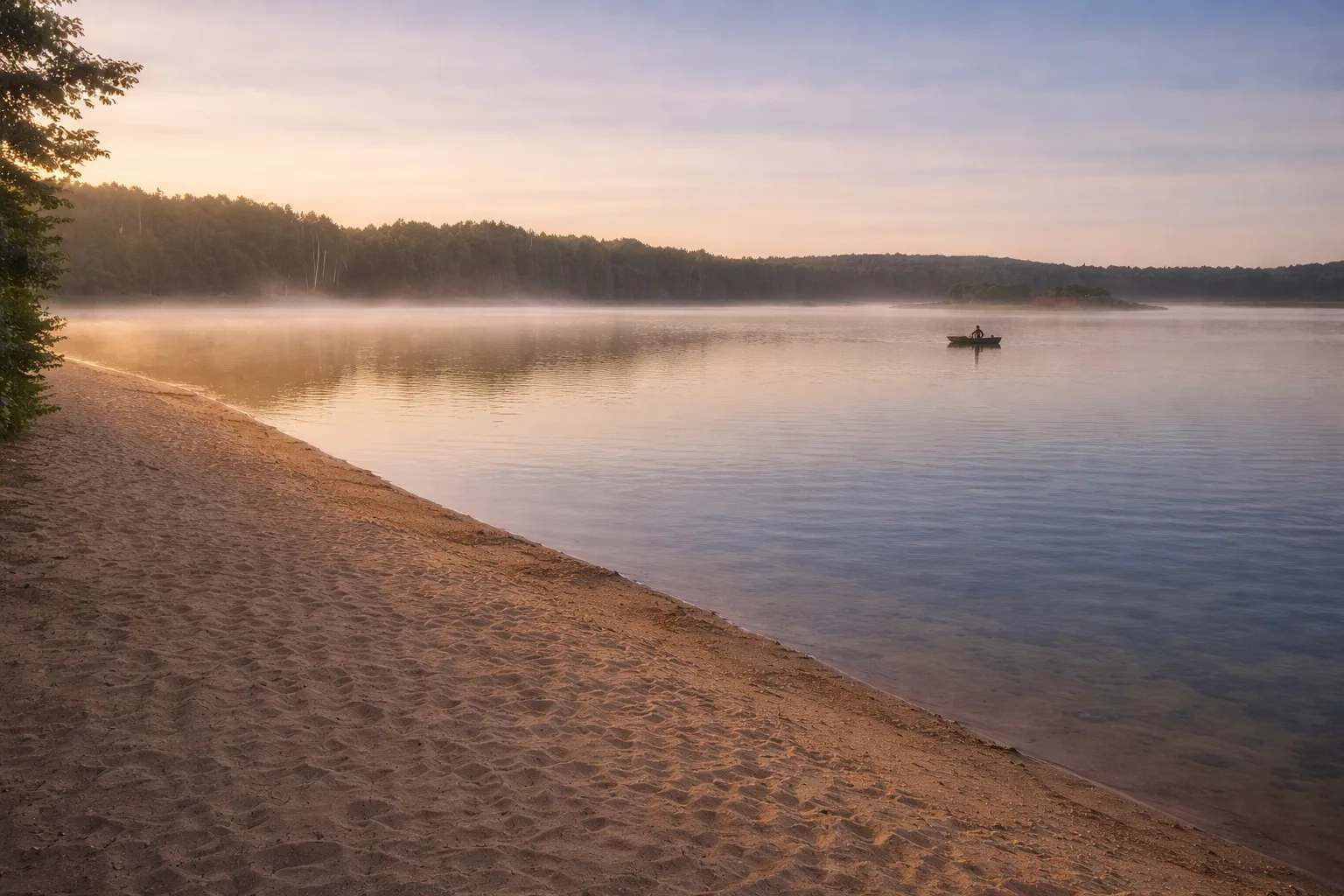 Pusta piaszczysta plaża nad jeziorem o poranku, spokojna tafla wody z lekką mgłą i mała łódka z wędkarzem na środku jeziora, otoczona lasem w miękkim świetle świtu -  Roztocze