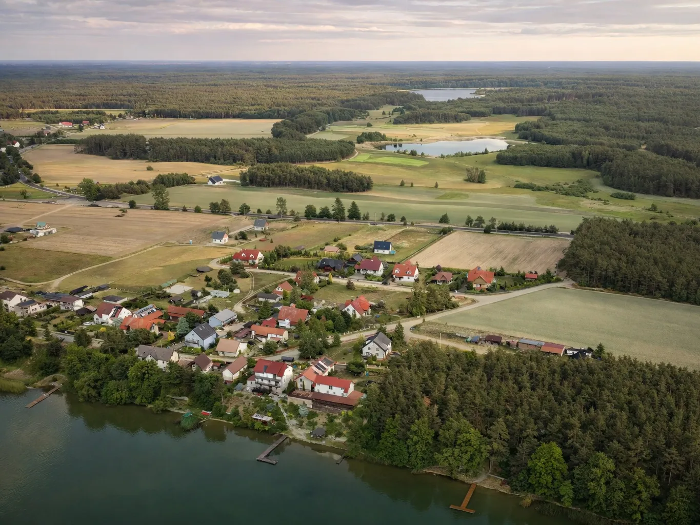 Wdzydze Tucholskie z lotu ptaka – zabudowa nad jeziorem, lasy i pola w okolicach Borów Tucholskich