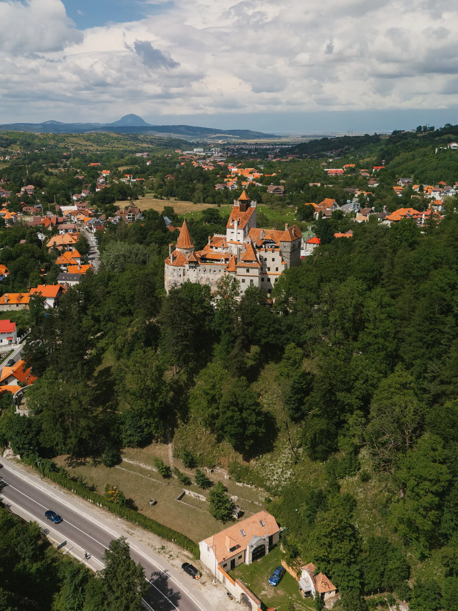 Zamek Bran w Rumunii widziany z drona, otoczony lasem i zabudową miejscowości Bran.