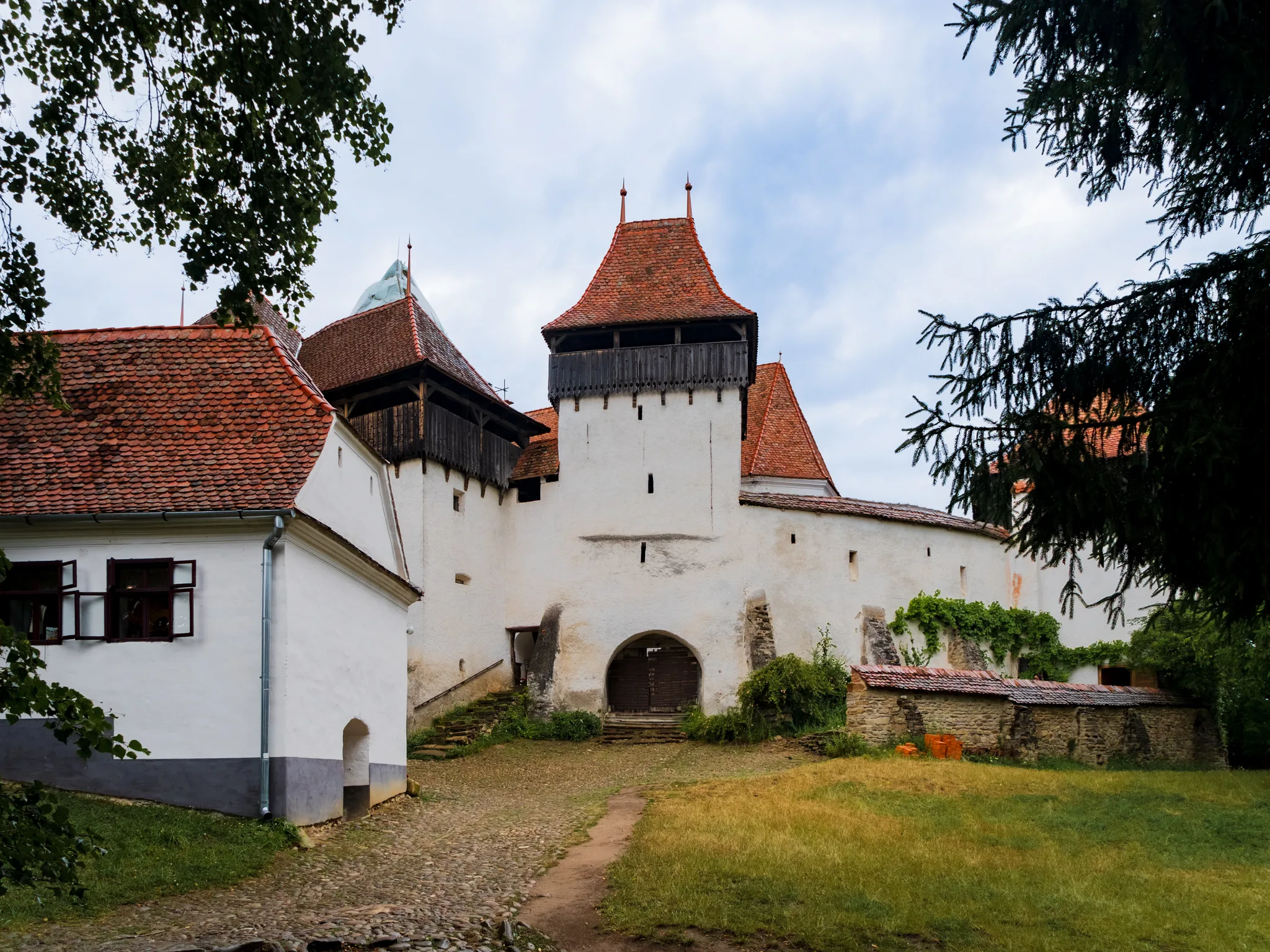 Kościół warowny w Viscri w Rumunii z kobietą stojącą na brukowanym dziedzińcu
