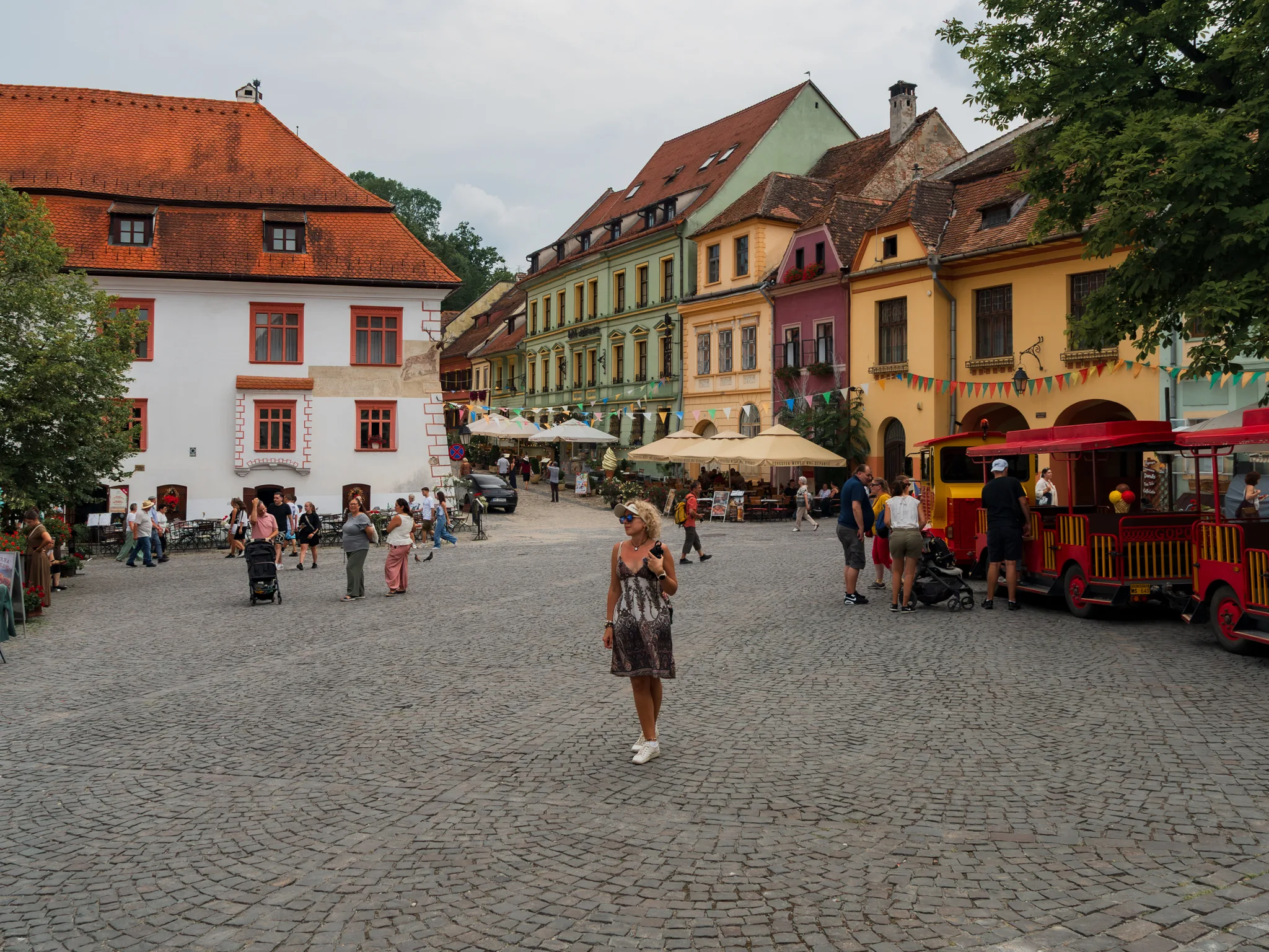 Plac Cytadeli z kolorowymi kamienicami i turystyczną kolejką w Sighișoarze.