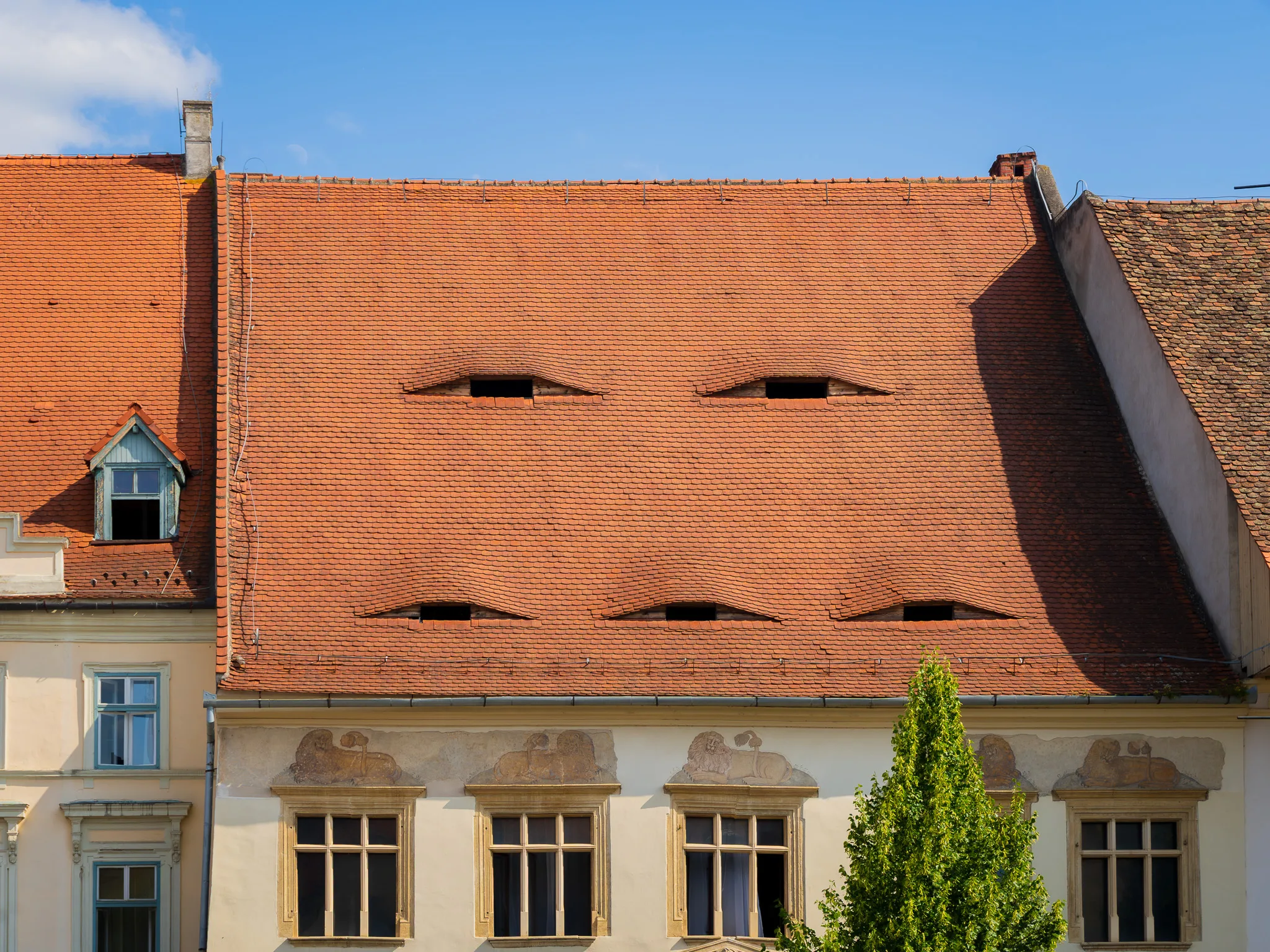 Kamienica z charakterystycznymi oknami przypominającymi oczy na czerwonym dachu w centrum Sybinu.