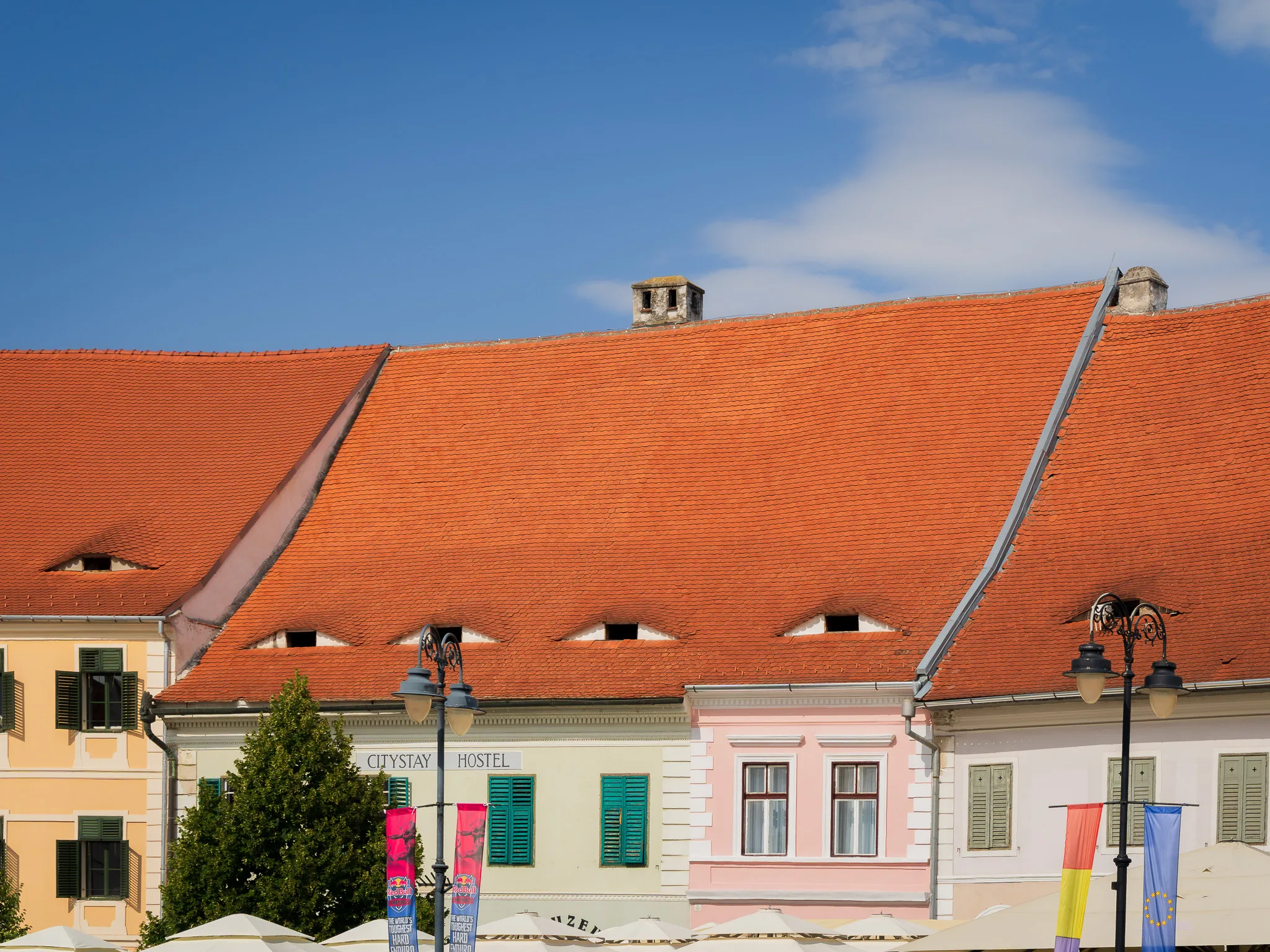 Kolorowe kamienice z czerwonymi dachami przy Dużym Rynku w Sybinie na tle błękitnego nieba.