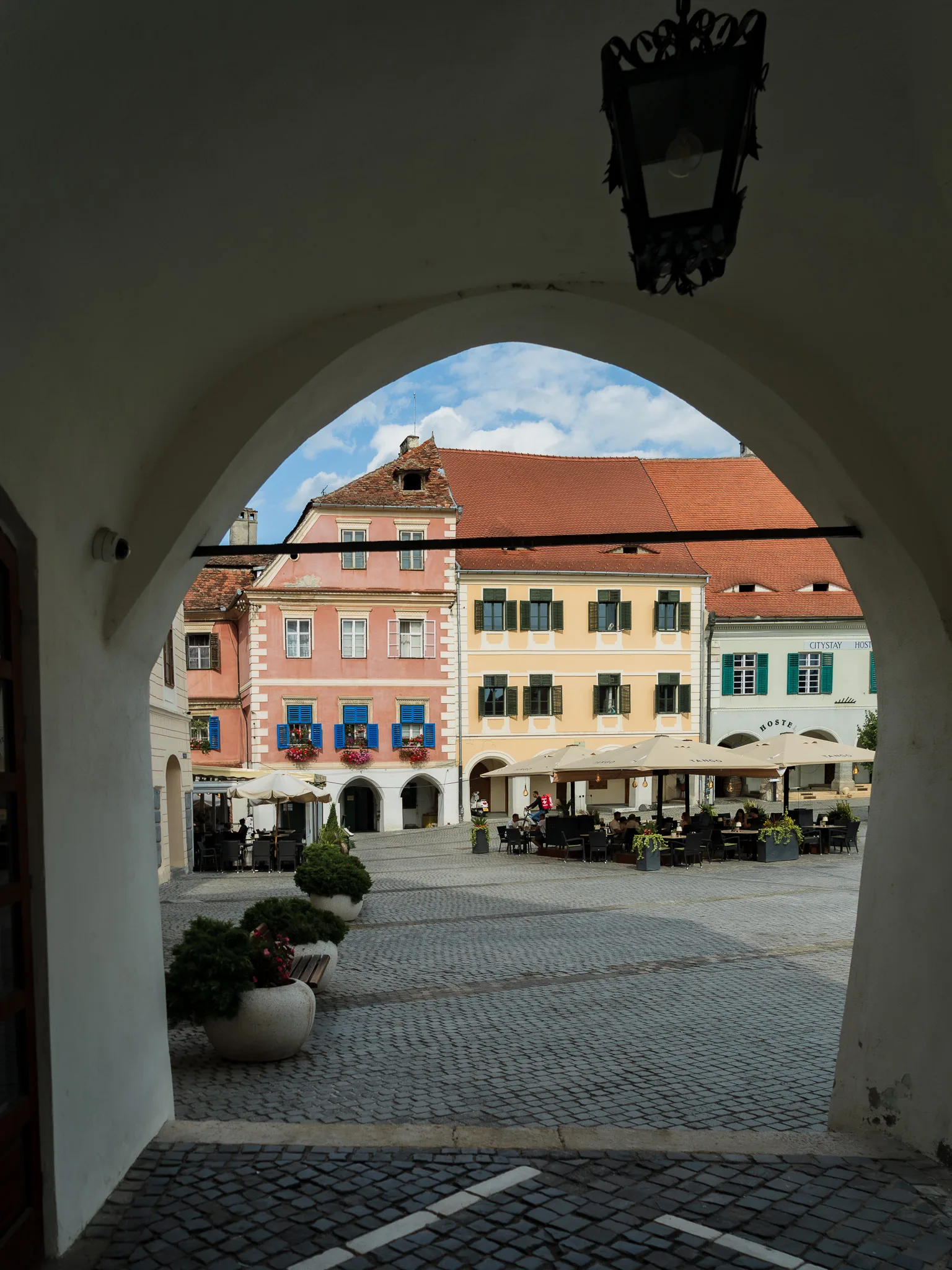 Widok na kolorowe kamienice i rynek w Sybinie przez łukowate przejście