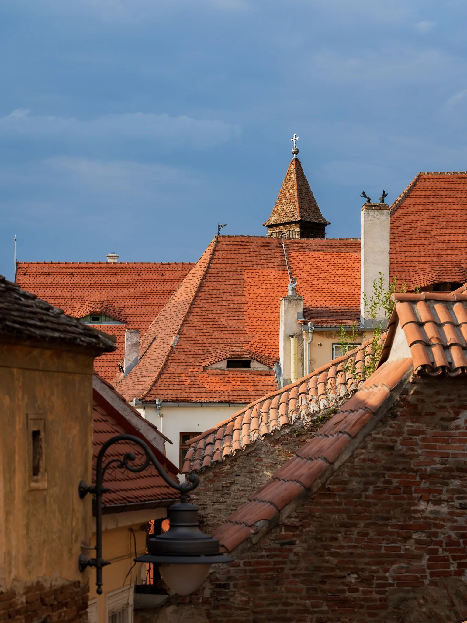 Czerwone dachy starych kamienic i wieżyczka widziane ponad zabudową historycznego centrum Sybinu.