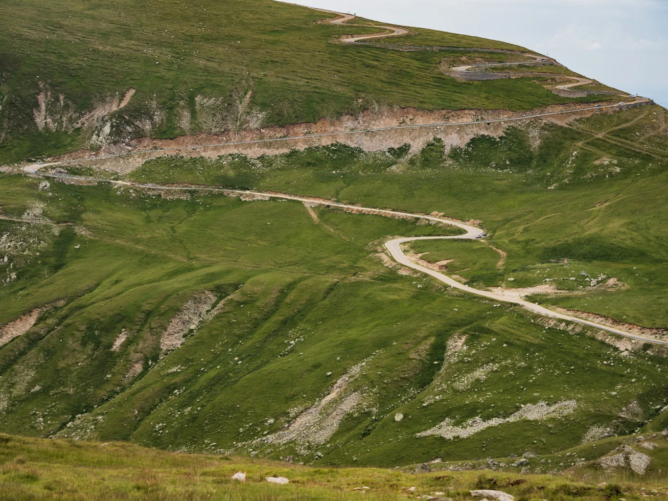Serpentyny Trasy Transalpina wijące się po zielonych, wysokogórskich zboczach w Rumunii.