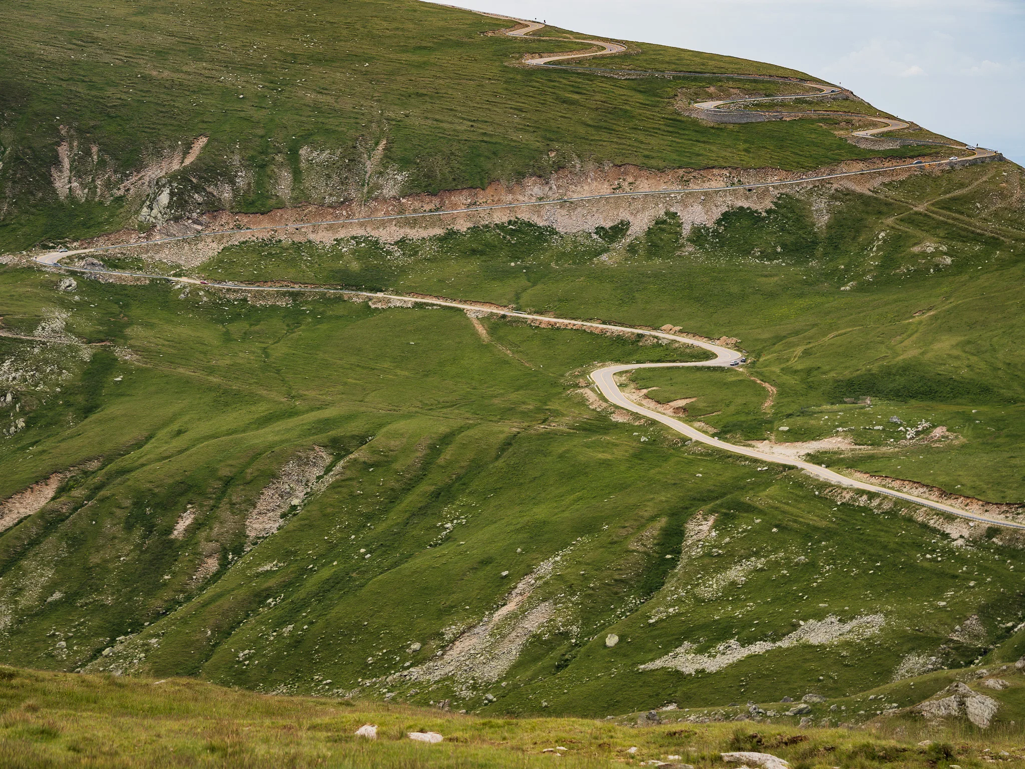 Serpentyny Trasy Transalpina wijące się po zielonych, wysokogórskich zboczach w Rumunii.