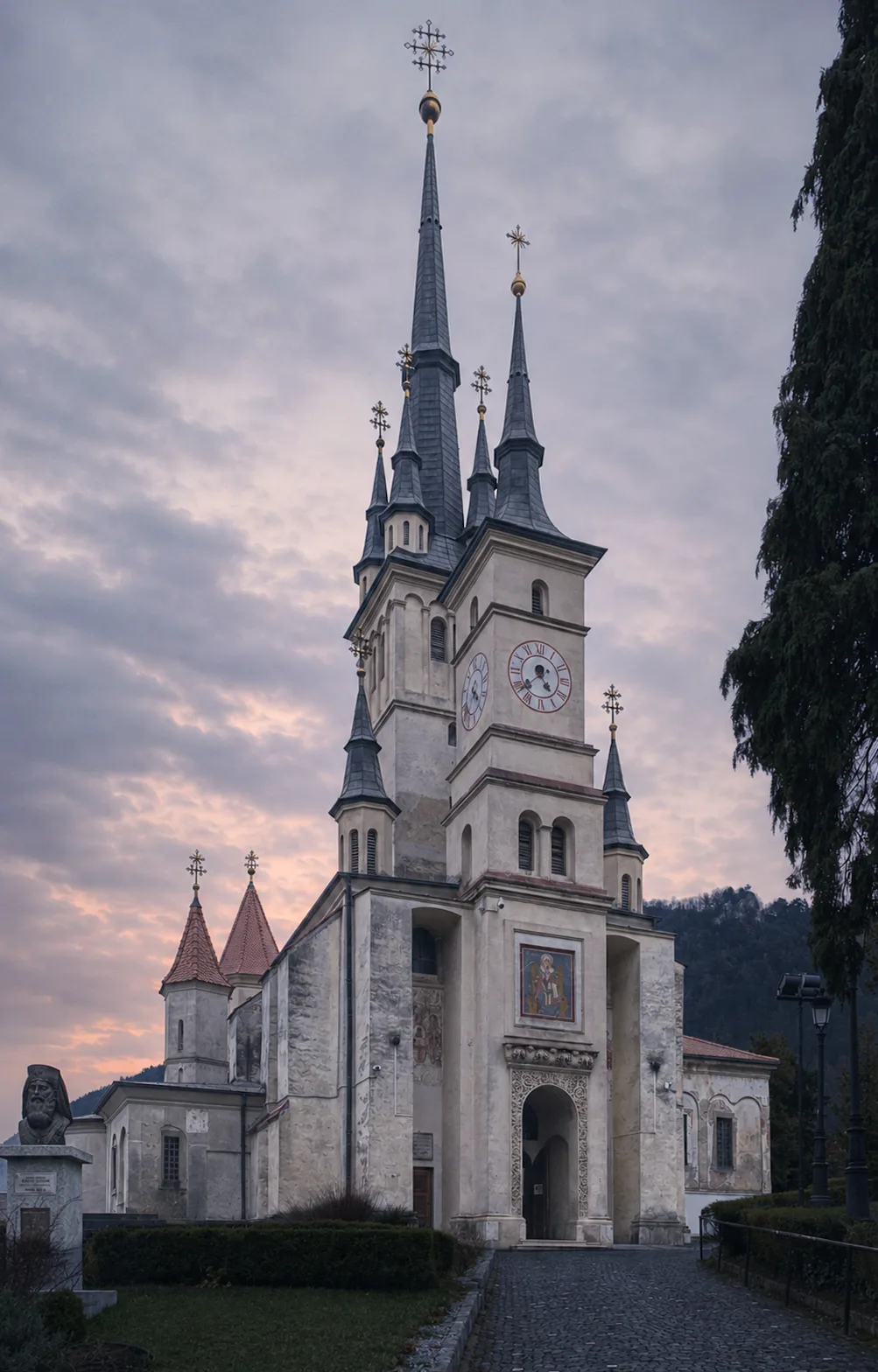 Kościół św. Mikołaja w Braszowie z wysokimi smukłymi wieżami na tle pochmurnego nieba.