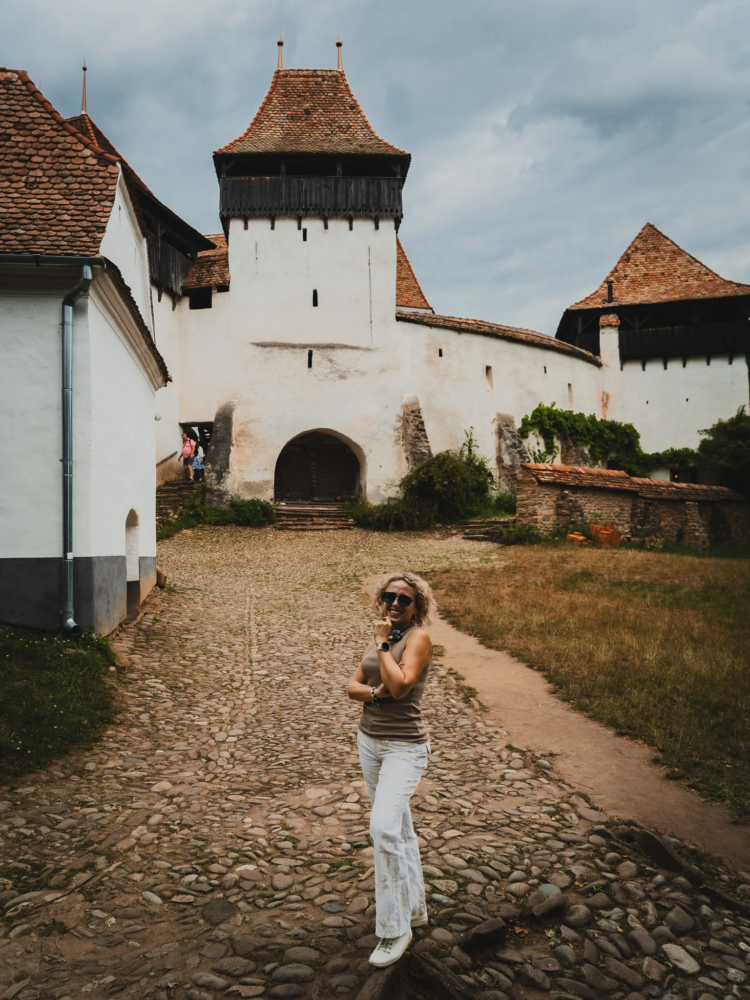 Kościół warowny w Viscri w Rumunii z kobietą stojącą na brukowanym dziedzińcu