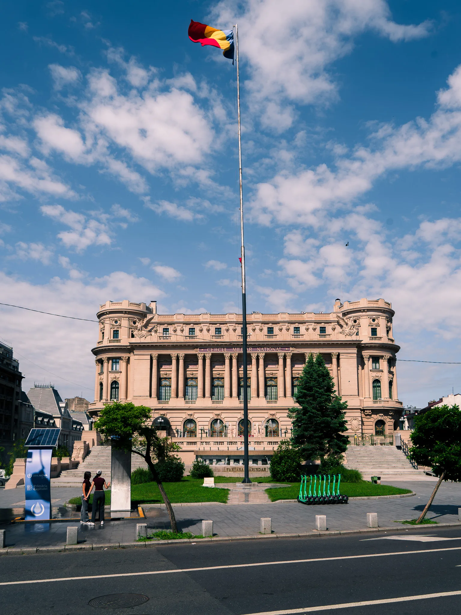 Pałac Narodowego Koła Wojskowego w Bukareszcie z dużą flagą Rumunii przed budynkiem.