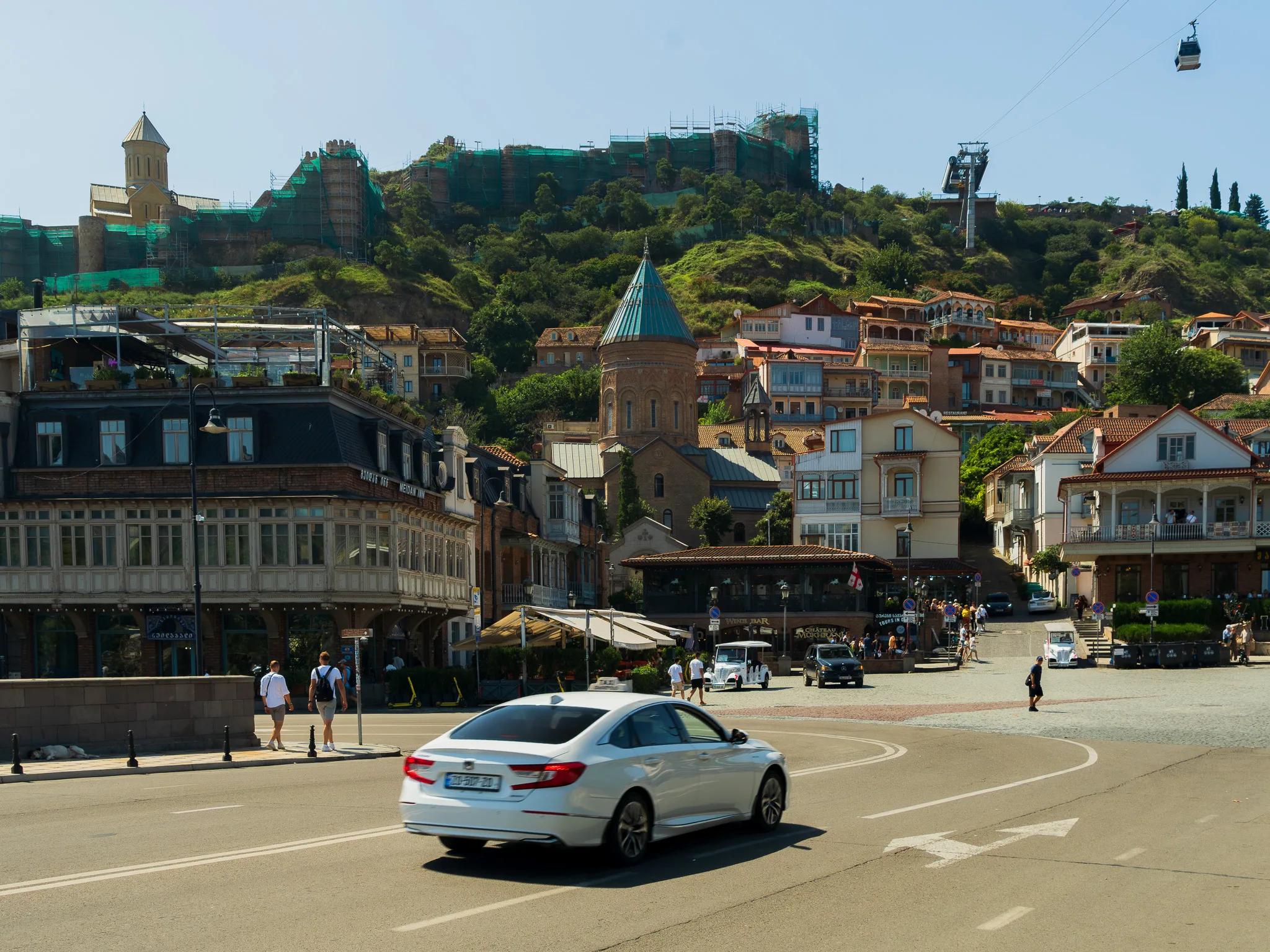 Plac Meidan i zabytkowa część Tbilisi z katedrą św. Jerzego, kolorowymi balkonami oraz twierdzą Narikala i kolejką linową na wzgórzu.