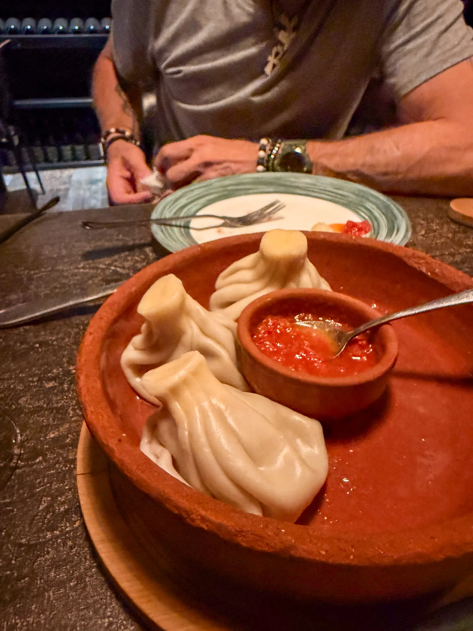 Gruzińskie chinkali podane w glinianym naczyniu z czerwonym sosem w restauracji w Tbilisi