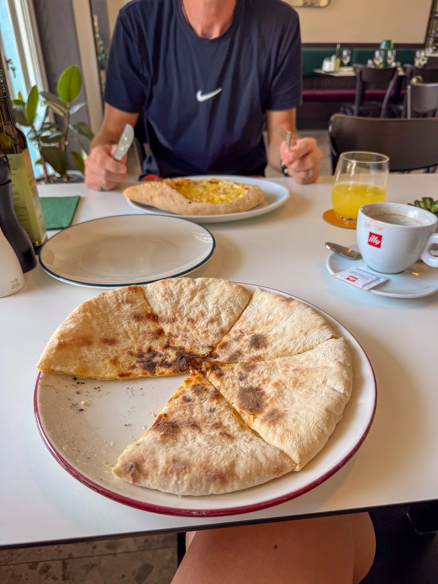 Tradycyjny gruziński placek nadziewany podany w restauracji w Tbilisi, z chaczapuri w tle.